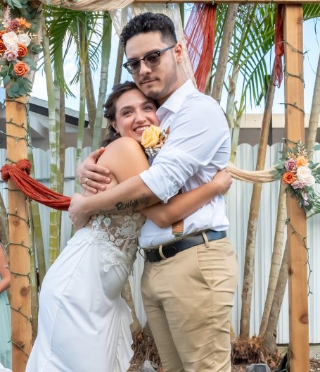 Couple embracing happily at their wedding, surrounded by their wedding arch in Miami by Iris Ramil Wedding Officiant