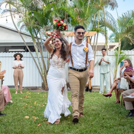 Bride and groom celebrate joyfully after their wedding ceremony in a garden setting.