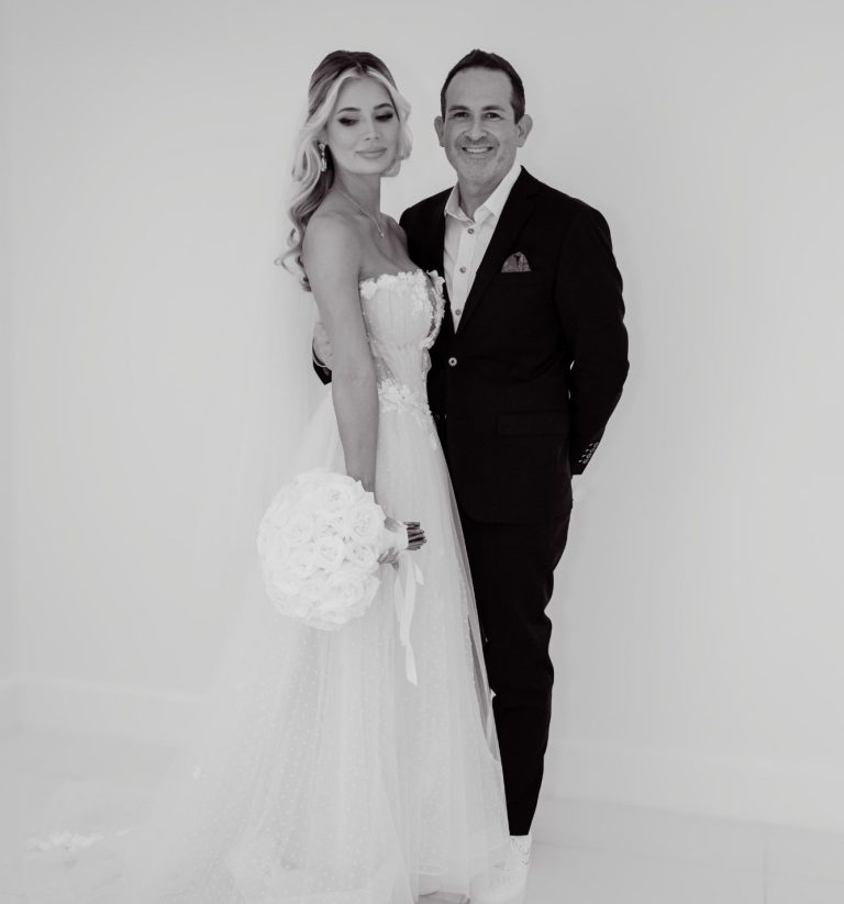 Just Married and on our way... A bride and groom hold hands, framed by two trees, in a sunny outdoor setting.