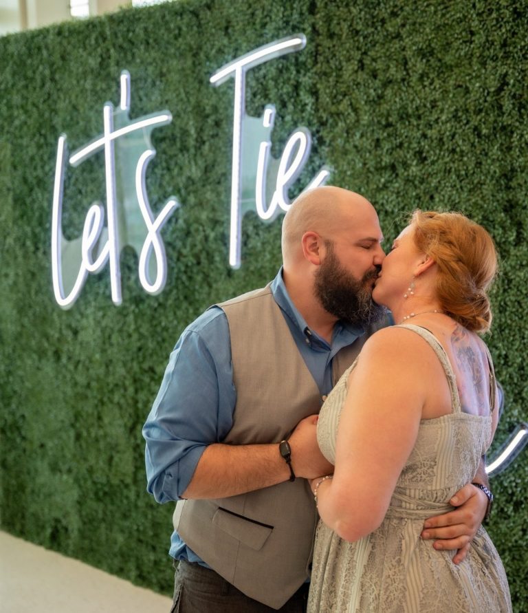 Couple sharing a kiss in front of a green wall at the Port of Miami - Virgin Cruise Lines