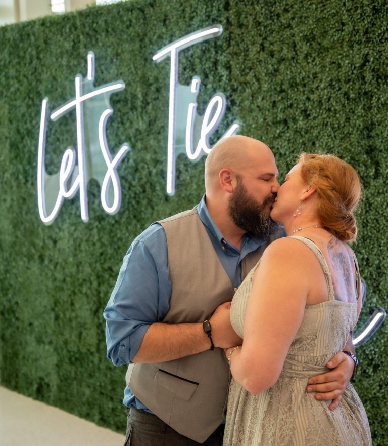 Couple sharing a kiss in front of a green wall at the Port of Miami - Virgin Cruise Lines