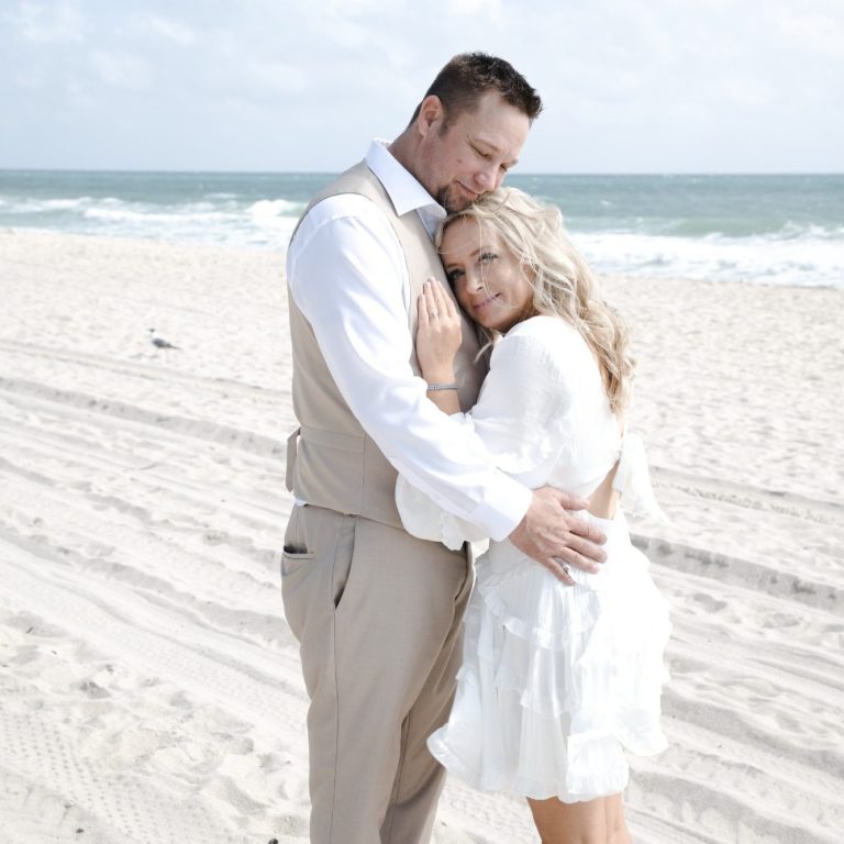 A wedding couple poses together, smiling, with bridal bouquet in hand in Miami