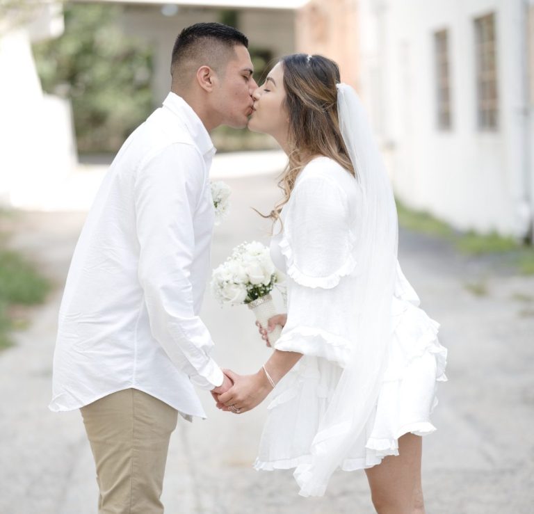 Couple kissing while holding hands in Pinecrest Florida by Iris Ramil Photographer and Wedding Officiant