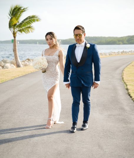 A couple walking along a waterfront path, the woman in a dress and the man in a suit.