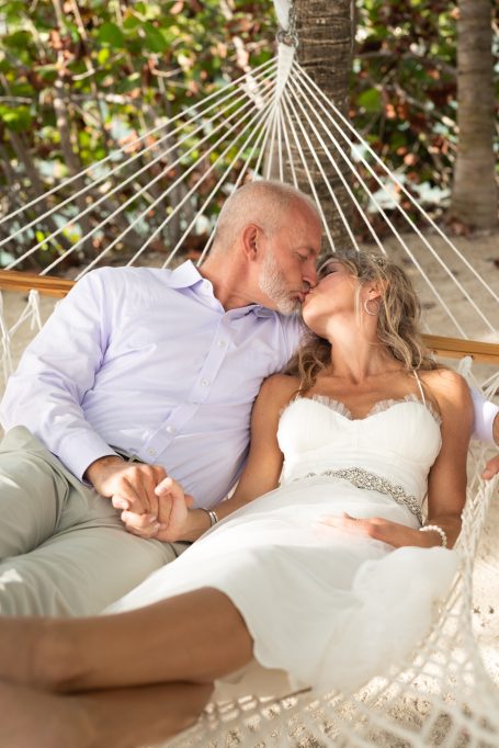 Couple in love sharing a kiss while lounging in a hammock, surrounded by greenery.
