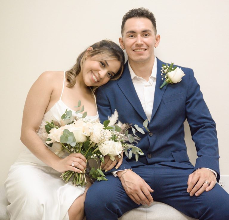 Groom and bride with bridal bouquet sitting on bench at Wedding Day Romance