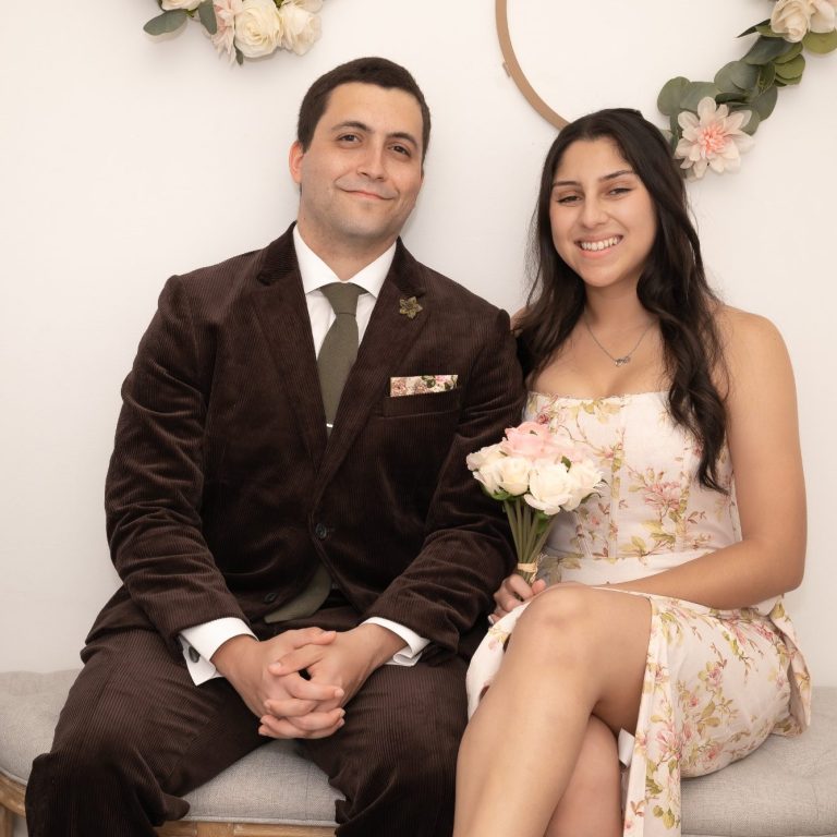 A wedding couple poses together, smiling, with bridal bouquet in hand in Miami