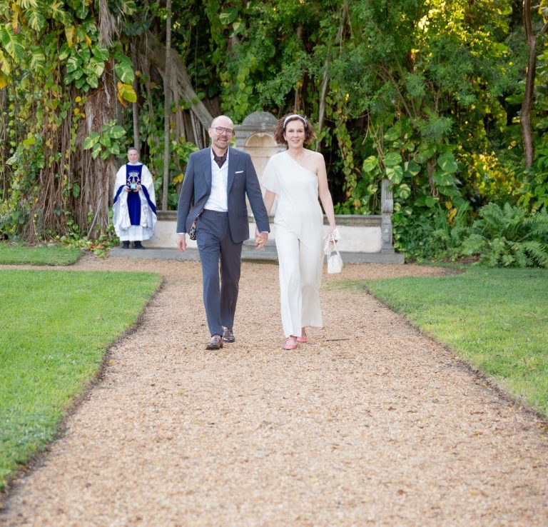 A wedding couple poses together, smiling, with bridal bouquet in hand in Miami