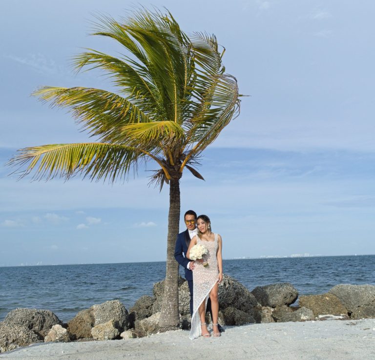 Bride & Groom under palm tree at beach side photographed by Iris Ramil