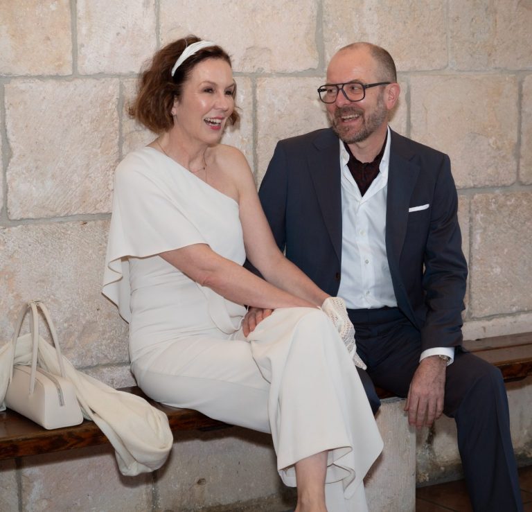 Bride and groom laughing sitting on a bench