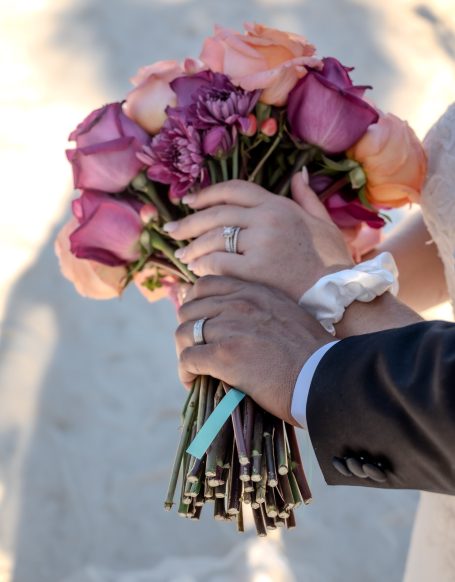 Bride and groom holding a bouquet of mixed roses with wedding rings in Key Largo