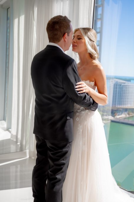 Bride and groom sharing a moment at a bright, elegant venue with a view.