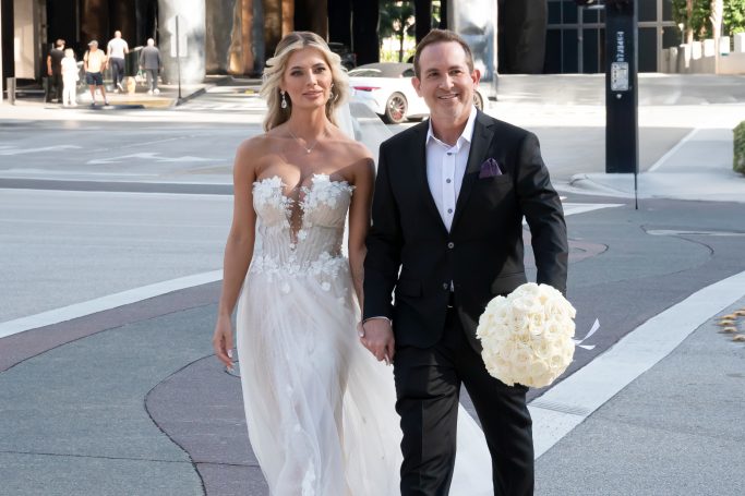 A bride and groom walking hand in hand, dressed elegantly for their wedding day.
