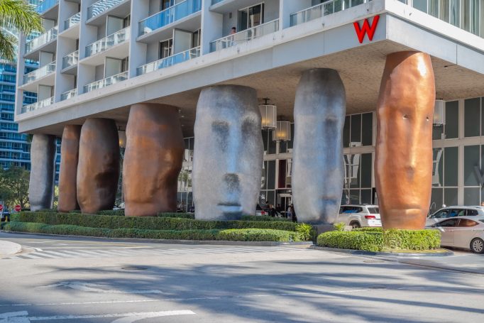 Large, unique sculptures of heads support the building's entrance at the W Hotel.