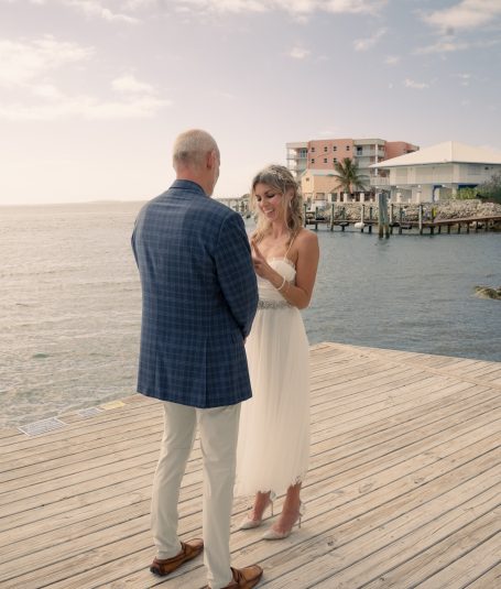 A couple exchanging vows on a dock by the water in a romantic setting.
